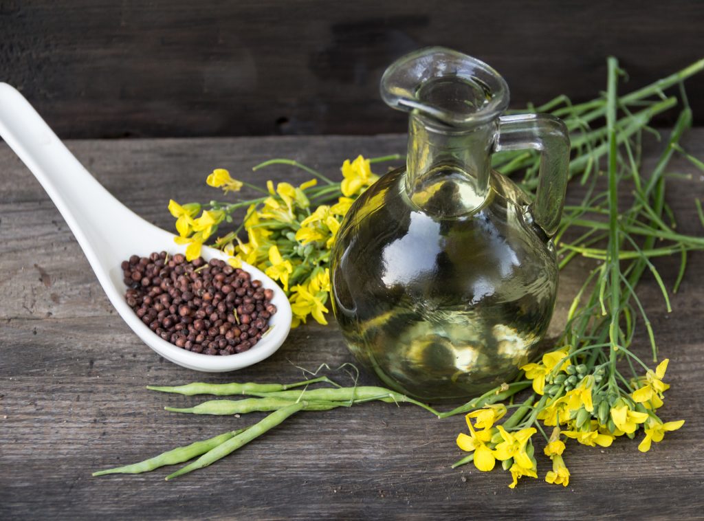 bottle rapeseed oil seeds and flowers on rustic wooden background